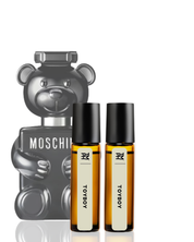 Two small bottles of perfume with black caps and white labels, placed in front of a Moschino bear-shaped product.